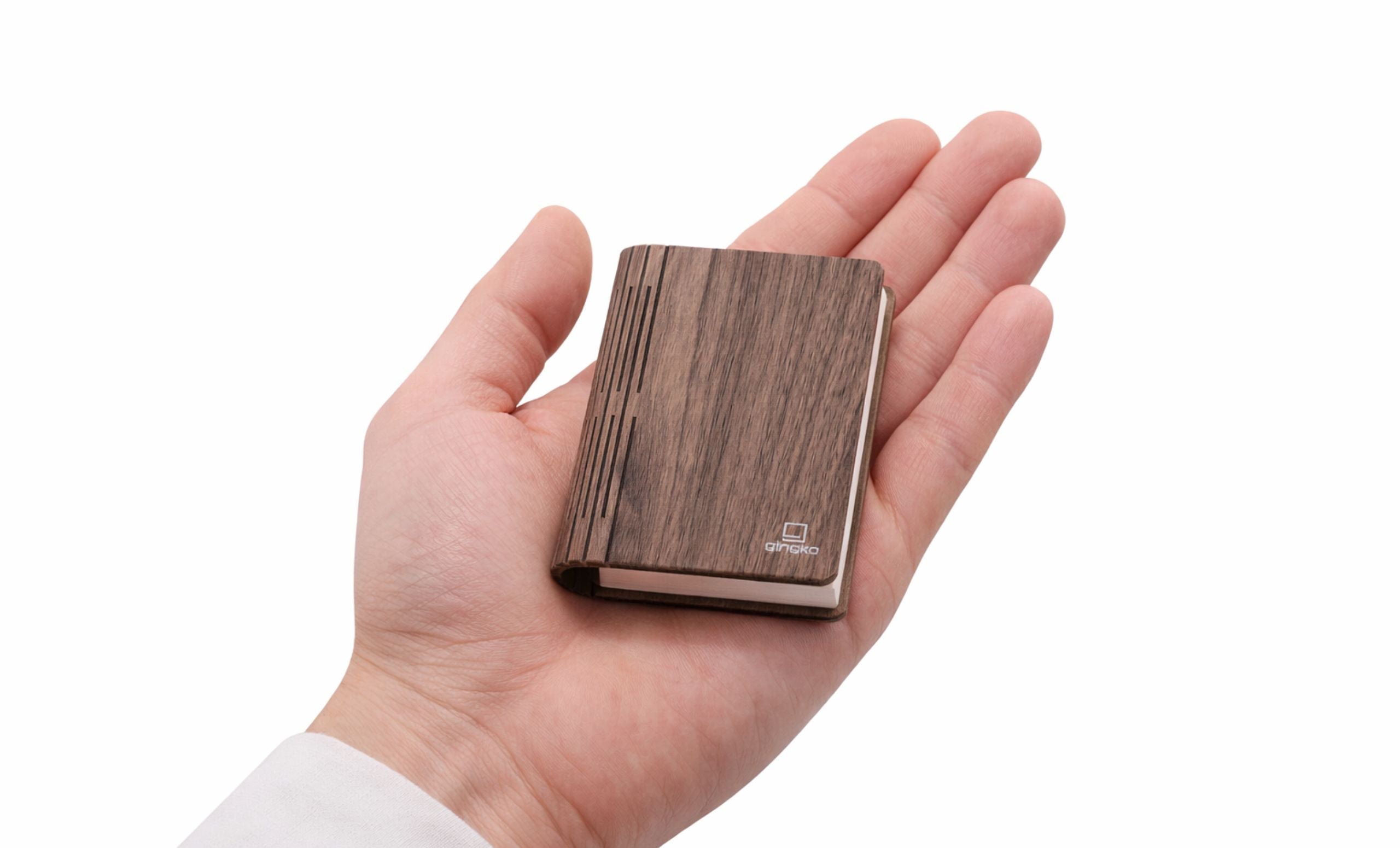 Gingko Palm Edition Smart Book Light in walnut finish held in the palm of a hand, showing compact size — closed position