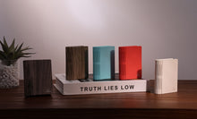 Load image into Gallery viewer, Five Gingko Smart Book Light Palm Edition units in walnut, dark wood, teal, red and cream finishes, closed and standing on a book
