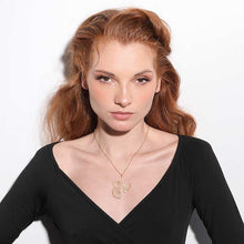 Load image into Gallery viewer, Model wearing RAS Ginkgo Biloba gold pendant necklace in studio, shown with black wrap top
