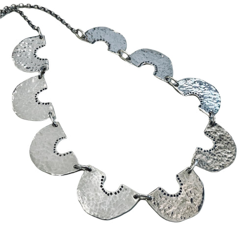 Silver necklace with half-circle links on a light gray background