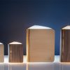Gingko Smart Book Light in natural maple and walnut, four sizes closed on white surface with blue background
