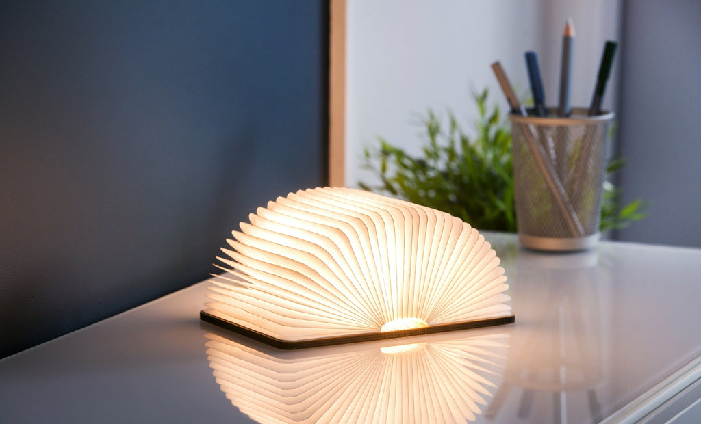 Gingko Smart Book Light in walnut, fully open at 180 degrees showing warm ambient light on desk