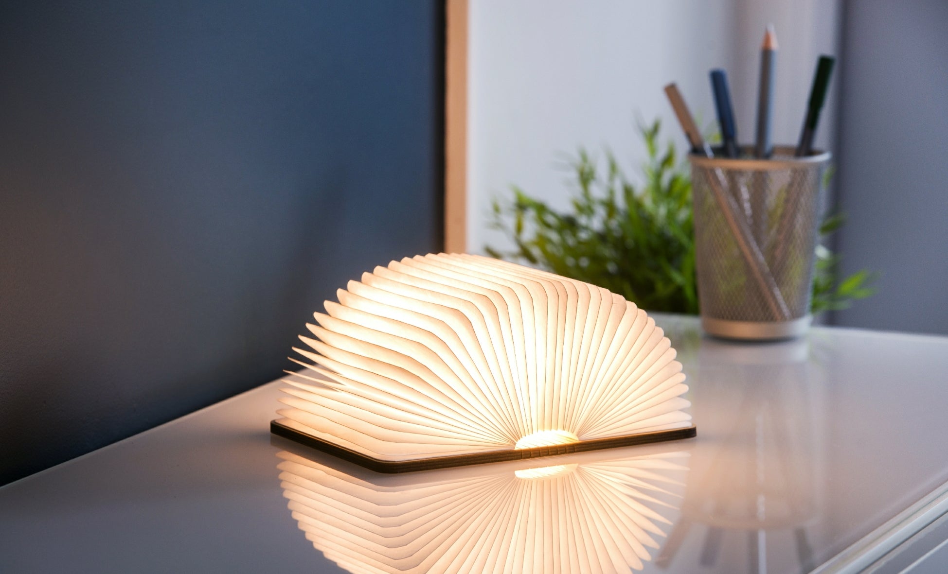 Gingko Smart Book Light in walnut, fully open at 180 degrees showing warm ambient light on desk